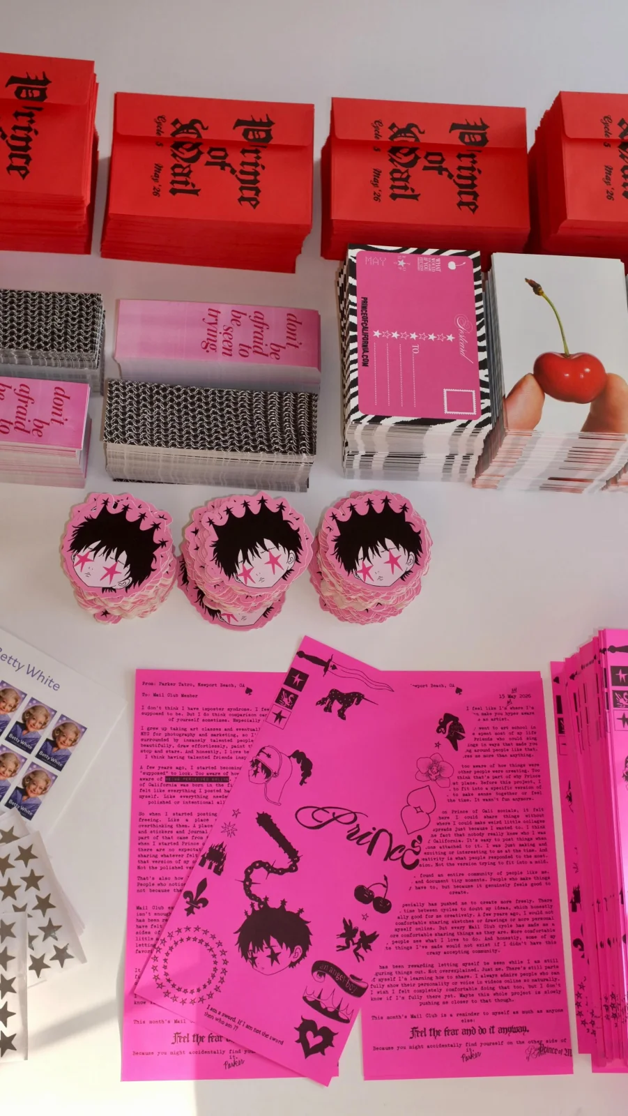 Prince of California’s May mail with red envelopes, pink letters, and cherry photography