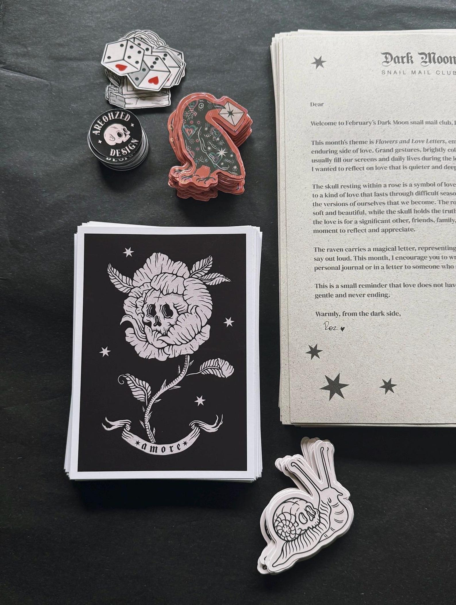 Dark Moon Snail Mail Club — February edition — skull rose prints, raven stickers and letters arranged in stacks during preparation