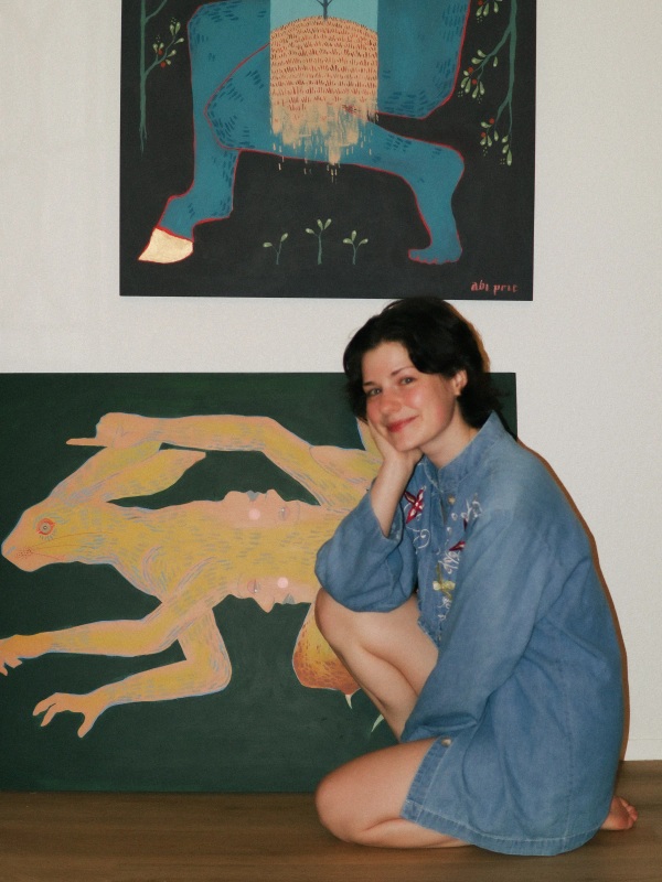 Abi Prie seated beside her paintings