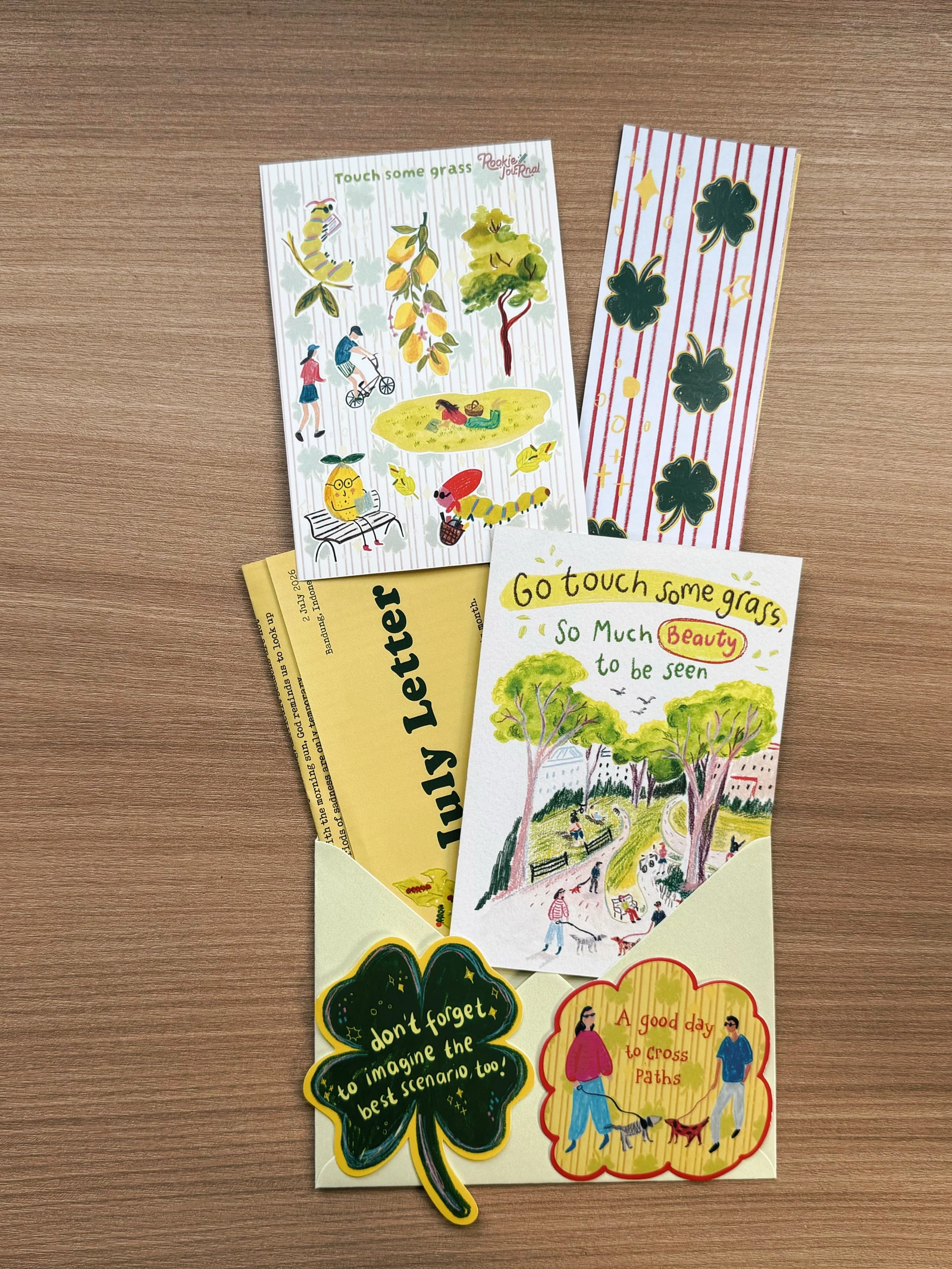 Rookie Journal Mail Club — July 2026 Touch Some Grass collection, photographed with letter, postcard, illustrated stickers and envelope